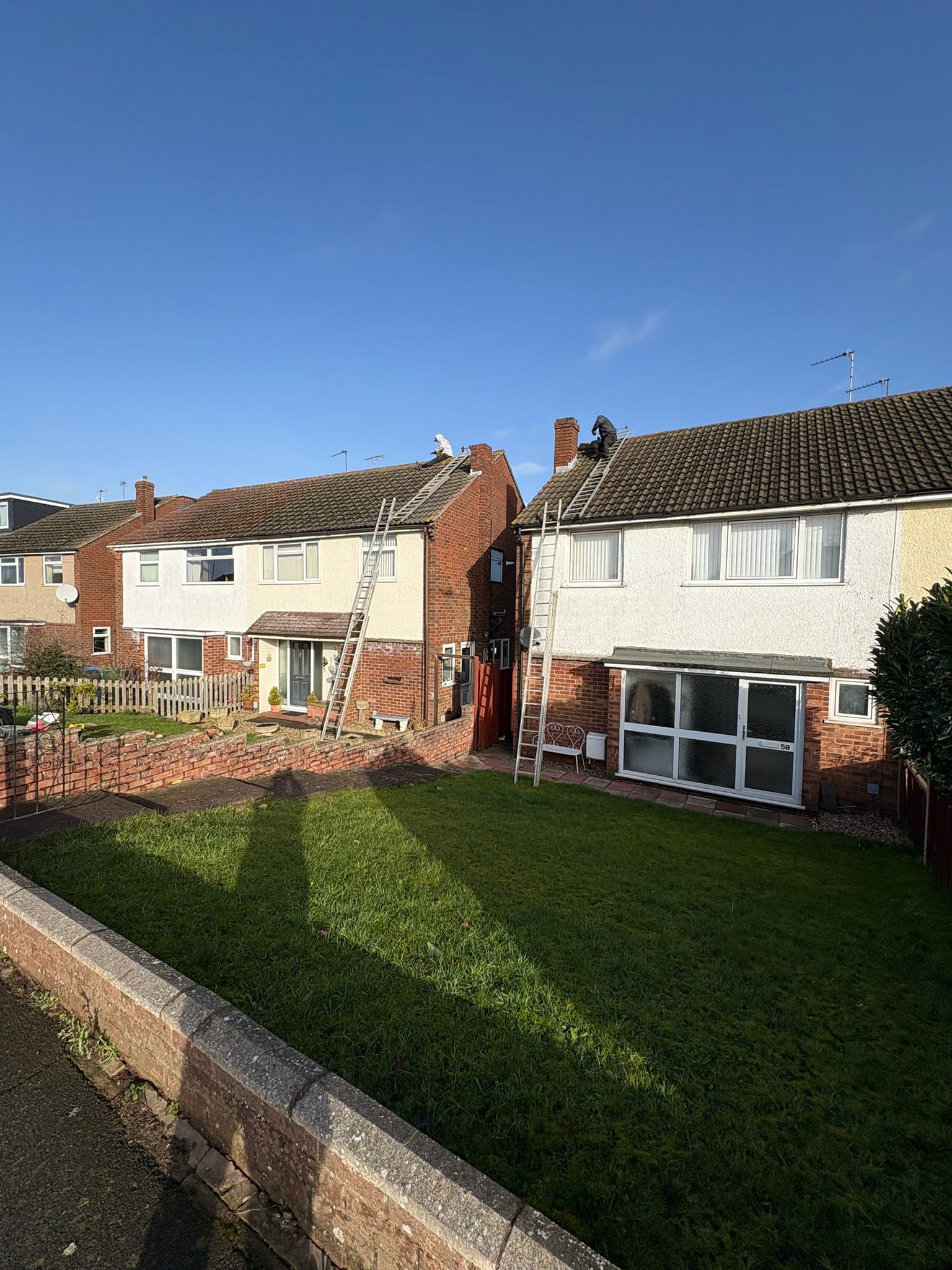 Two semi-detached houses with ladders during roofing work