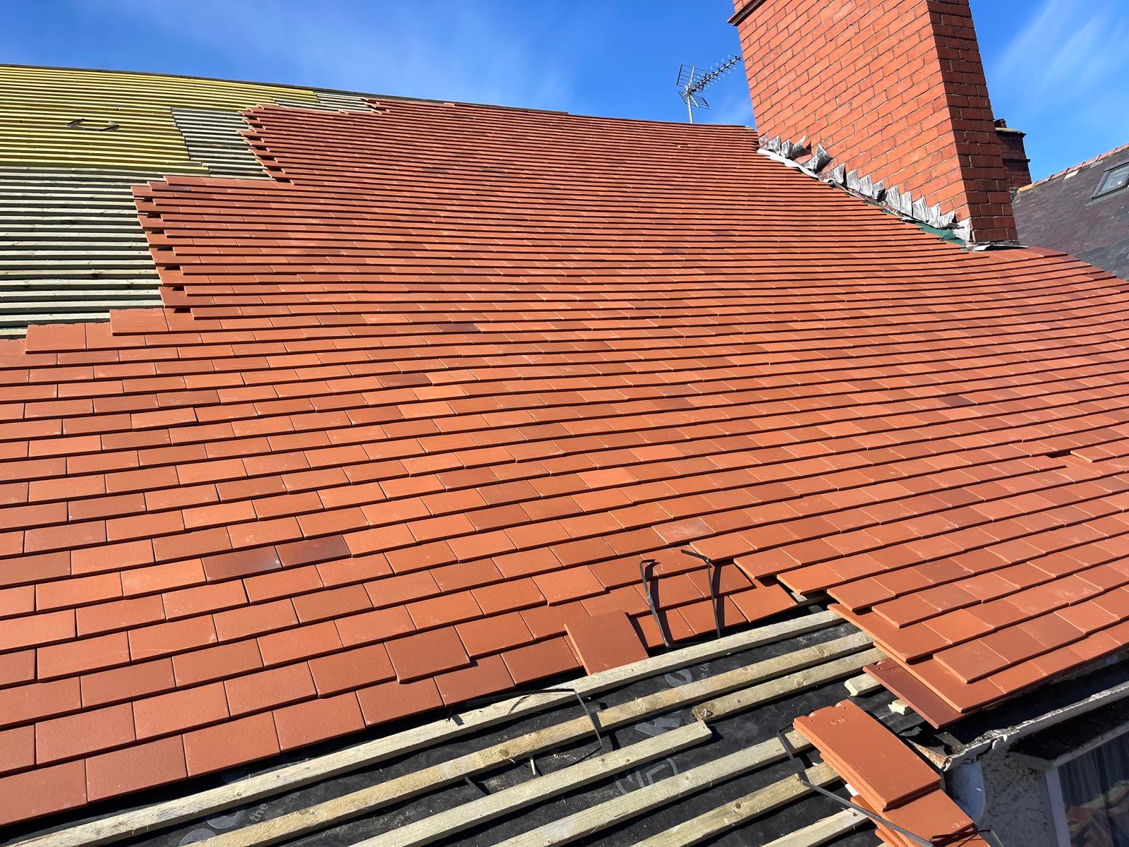 New clay tile roof installation close-up with fresh ridge tiles and lead flashing